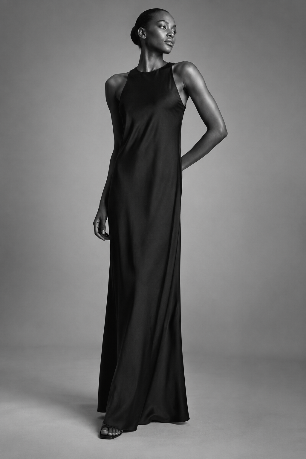 Sleeveless black column dress on a model in a gray studio